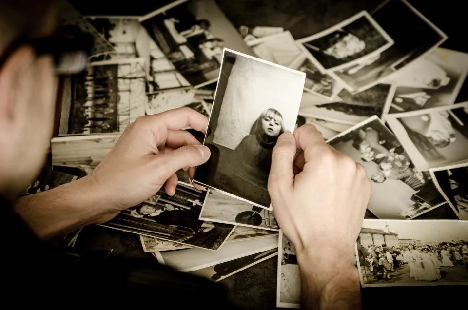 Manos sujetando fotografías impresas sobre una mesa