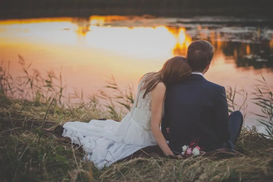 Pareja sentada junto a un lago al atardecer